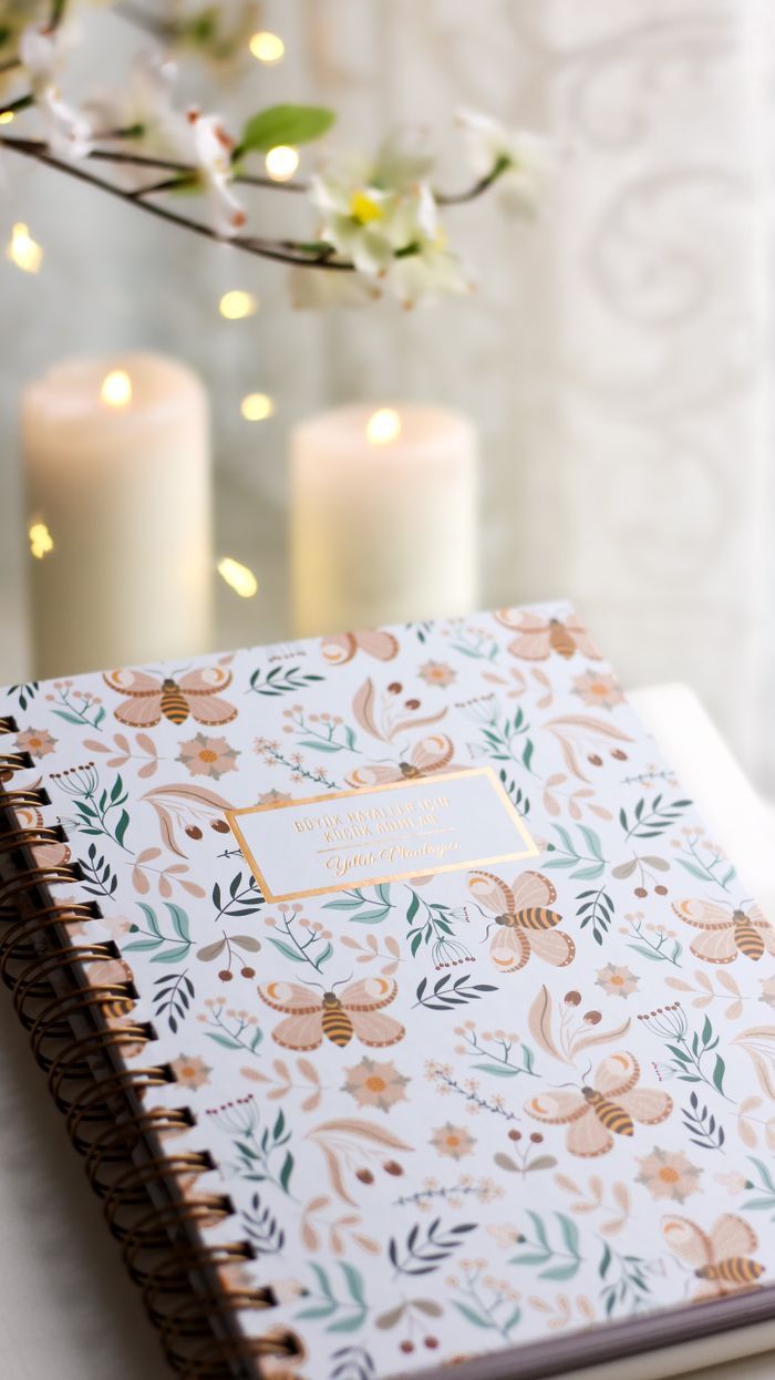 Stylish floral patterned notebook with glowing candles and decorative lights, creating a cozy ambiance.
