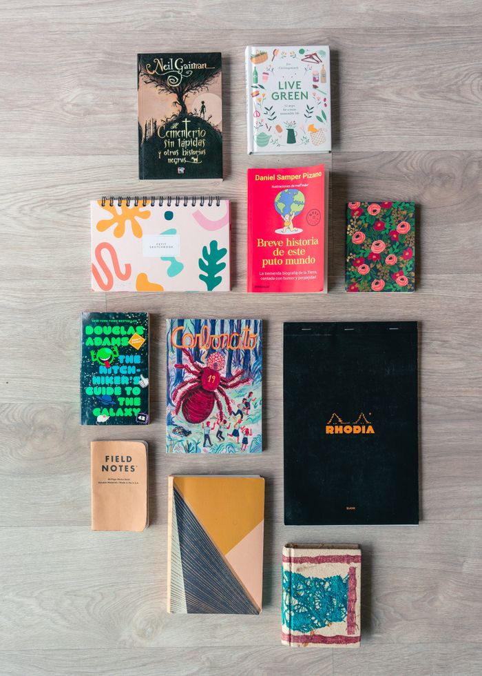 A vibrant flat lay of books and notebooks on a wooden surface, showcasing diverse designs and genres.